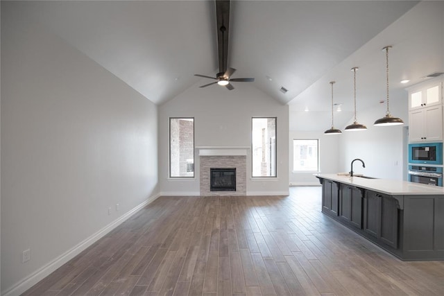 8108 NW 154th St, Edmond, OK 73013 - unfurnished living room with beamed ceiling, a sink, wood finished floors, a ceiling fan, and a fireplace