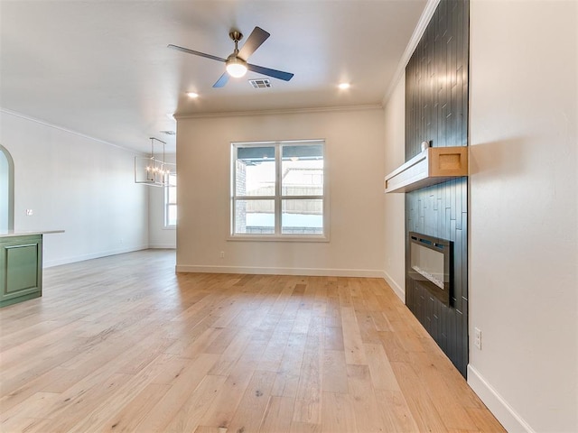 unfurnished living room with ceiling fan with notable chandelier, light hardwood / wood-style floors, ornamental molding, and a tile fireplace