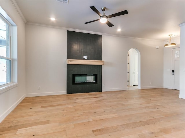 unfurnished living room featuring a large fireplace, light hardwood / wood-style floors, ceiling fan, and crown molding