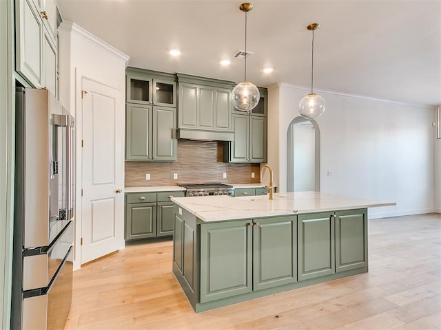 kitchen with a center island with sink, green cabinets, light stone counters, and high quality fridge