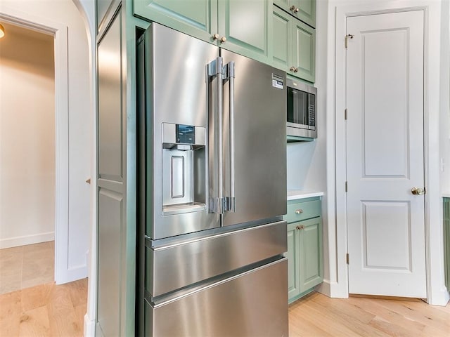 kitchen with stainless steel appliances, light hardwood / wood-style floors, and green cabinetry