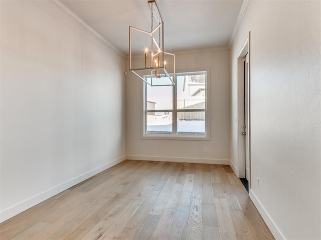 unfurnished dining area featuring light hardwood / wood-style floors, ornamental molding, and a chandelier