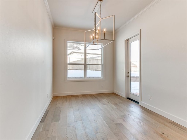 unfurnished dining area featuring ornamental molding, a chandelier, and light hardwood / wood-style floors