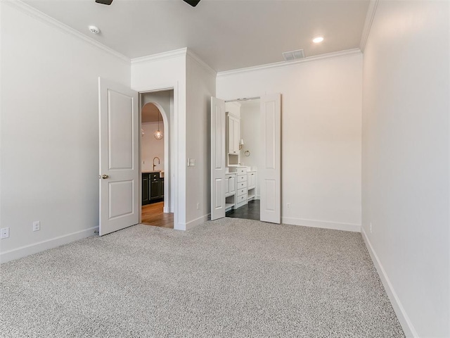 unfurnished bedroom featuring ornamental molding, carpet floors, ceiling fan, and ensuite bath