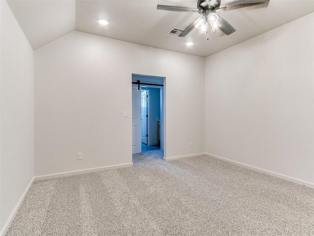 empty room with vaulted ceiling, a barn door, ceiling fan, and carpet