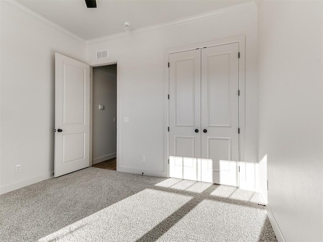 unfurnished bedroom featuring ornamental molding, carpet flooring, and a closet