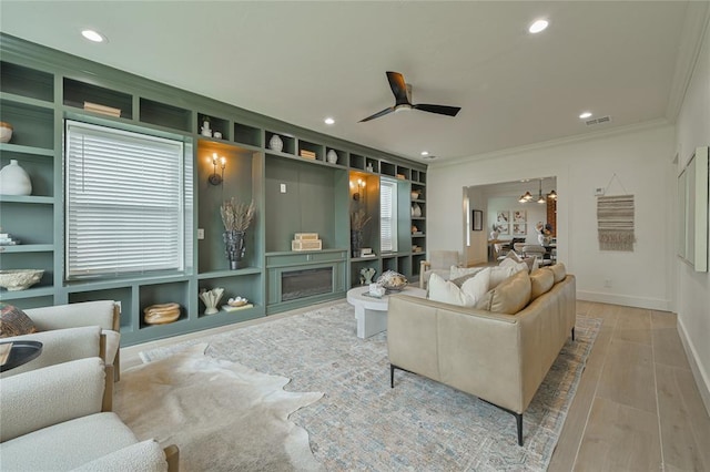 home theater featuring built in shelves, ceiling fan, and ornamental molding