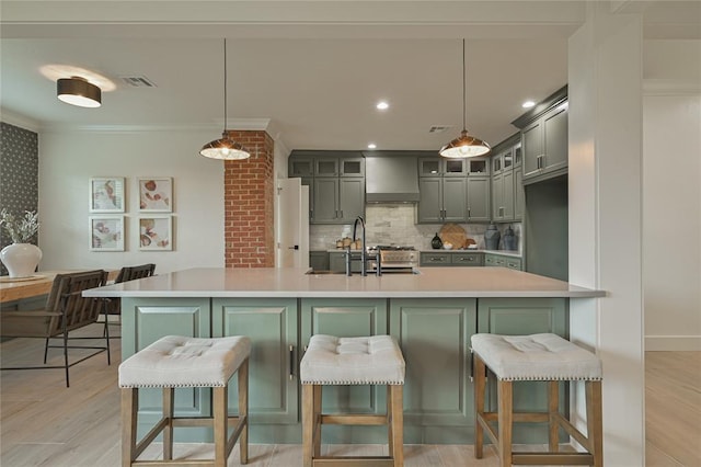 kitchen featuring wall chimney exhaust hood, decorative light fixtures, backsplash, and a breakfast bar