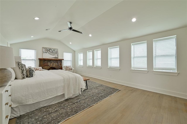 bedroom featuring multiple windows, ceiling fan, vaulted ceiling, and light wood-type flooring