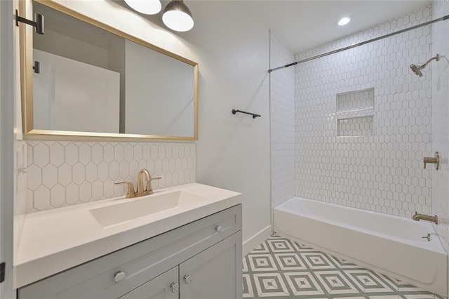 bathroom with decorative backsplash, vanity, and tiled shower / bath