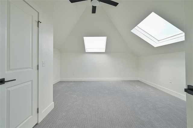 bonus room with light carpet, ceiling fan, and vaulted ceiling with skylight