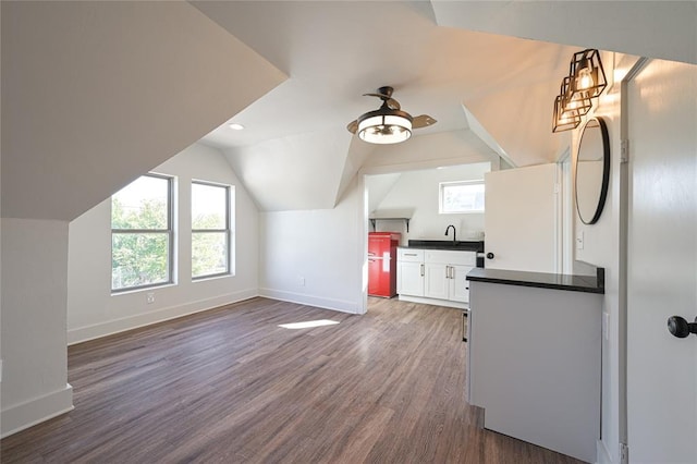 kitchen with white cabinetry, sink, ceiling fan, dark wood-type flooring, and vaulted ceiling