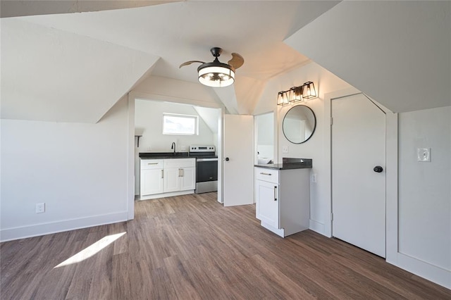 kitchen featuring stainless steel electric stove, ceiling fan, hardwood / wood-style flooring, white cabinetry, and lofted ceiling