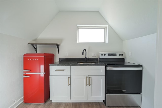 kitchen with stainless steel range with electric stovetop, white cabinets, lofted ceiling, and sink