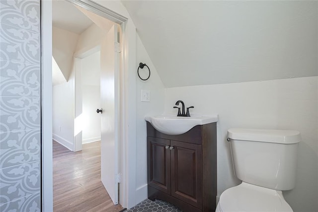 bathroom featuring hardwood / wood-style floors, vanity, toilet, and lofted ceiling