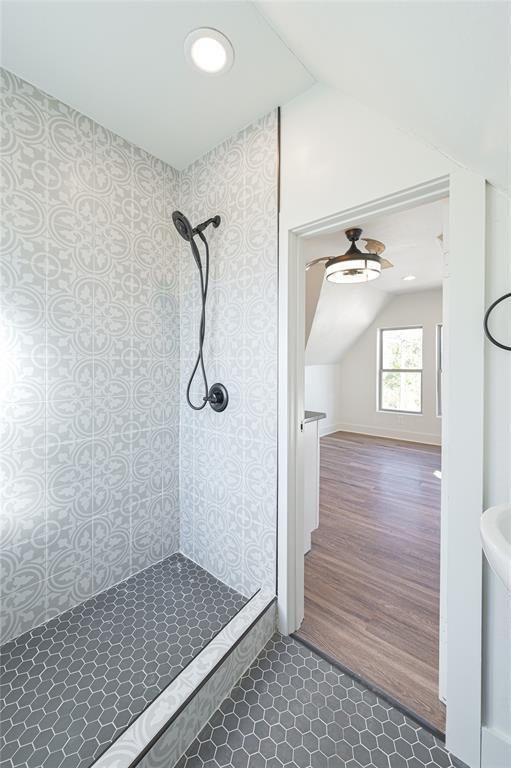 bathroom with wood-type flooring, lofted ceiling, and tiled shower