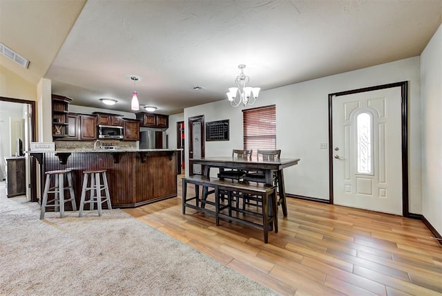 dining space featuring sink, an inviting chandelier, light hardwood / wood-style floors, and plenty of natural light