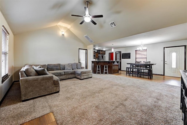 living room featuring ceiling fan with notable chandelier, carpet floors, and lofted ceiling