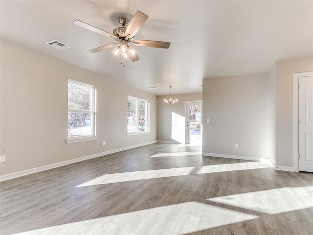 spare room featuring ceiling fan with notable chandelier and light hardwood / wood-style flooring