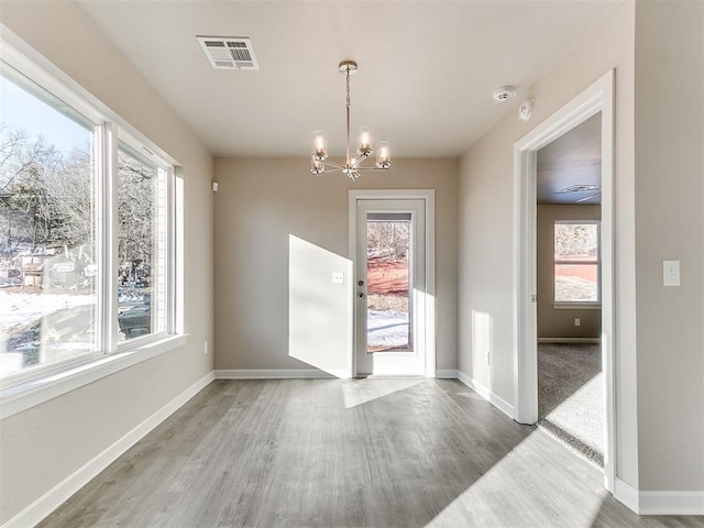 unfurnished dining area featuring hardwood / wood-style floors and a chandelier