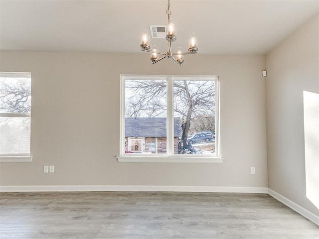 unfurnished dining area with light wood-type flooring and a notable chandelier