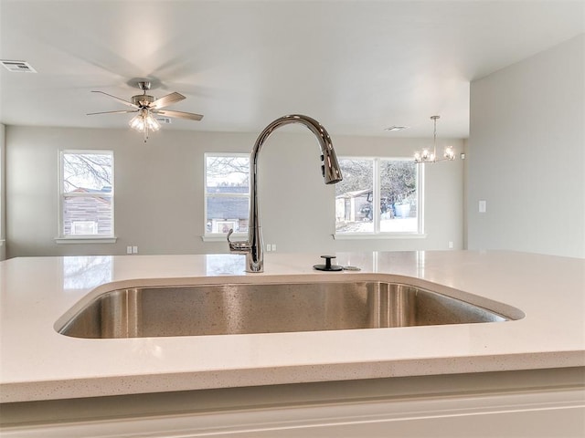 details featuring decorative light fixtures, light stone countertops, ceiling fan with notable chandelier, and sink