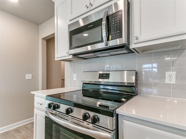 kitchen featuring stainless steel appliances, light wood-type flooring, backsplash, and white cabinetry