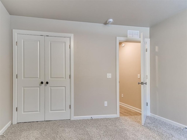 unfurnished bedroom with a closet and light carpet