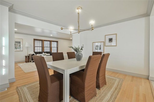 dining area featuring light wood-type flooring, crown molding, and a notable chandelier