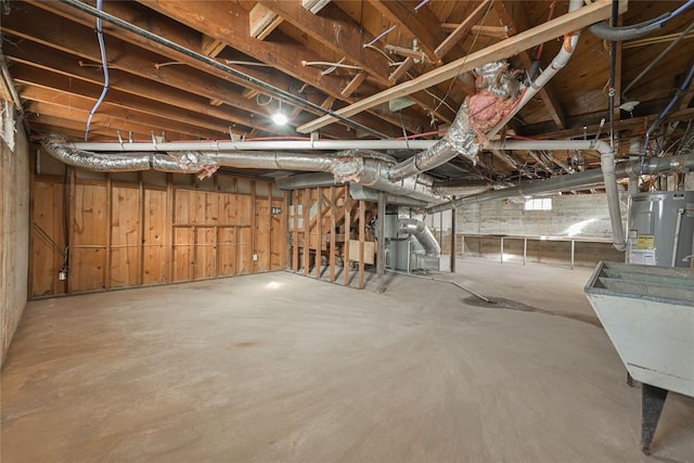 basement with water heater, wooden walls, and sink