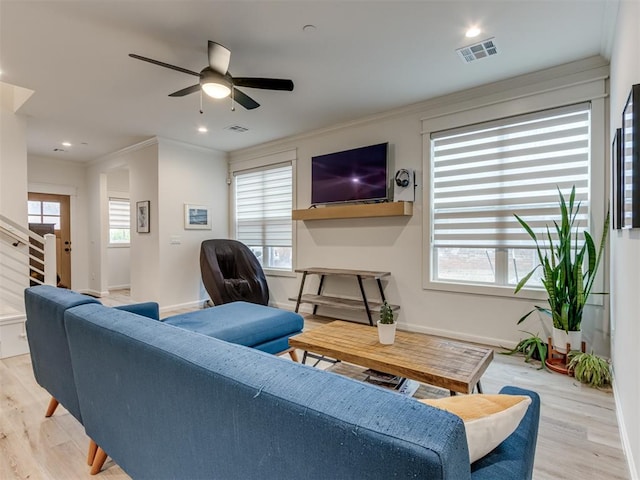 living room with ceiling fan, plenty of natural light, crown molding, and light hardwood / wood-style flooring