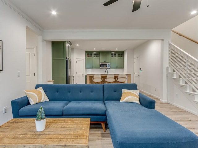 living room featuring ceiling fan, crown molding, and light hardwood / wood-style floors