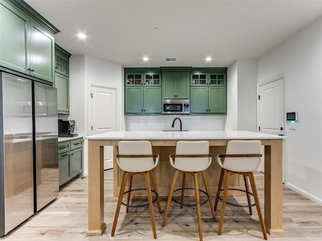 kitchen with a kitchen bar, stainless steel appliances, and green cabinetry