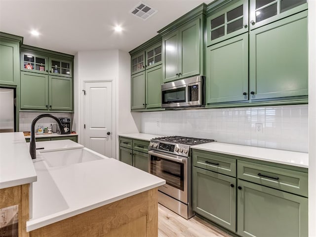 kitchen featuring tasteful backsplash, appliances with stainless steel finishes, sink, and green cabinetry