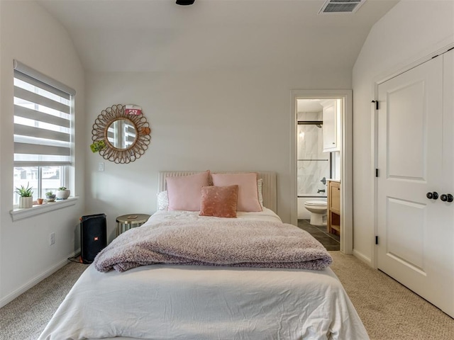 carpeted bedroom featuring ensuite bath and vaulted ceiling