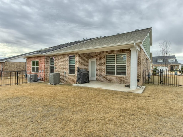 back of property with a lawn, central air condition unit, and a patio area