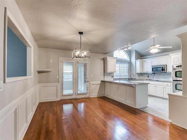 kitchen featuring hanging light fixtures, appliances with stainless steel finishes, white cabinets, and kitchen peninsula