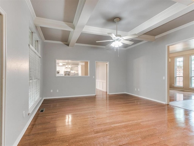 empty room with coffered ceiling, ornamental molding, beam ceiling, and light wood-type flooring