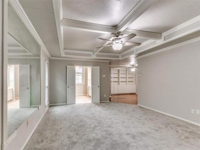 interior space with carpet flooring, coffered ceiling, ceiling fan, crown molding, and beam ceiling