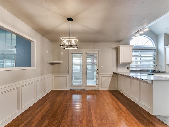 unfurnished dining area with vaulted ceiling, dark hardwood / wood-style flooring, a chandelier, and sink