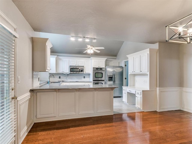 kitchen with stainless steel appliances, sink, white cabinets, and kitchen peninsula