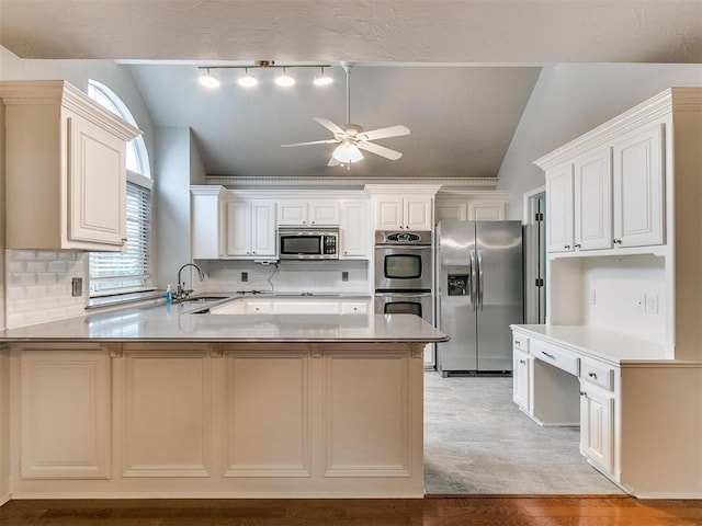 kitchen with appliances with stainless steel finishes, lofted ceiling, sink, decorative backsplash, and kitchen peninsula