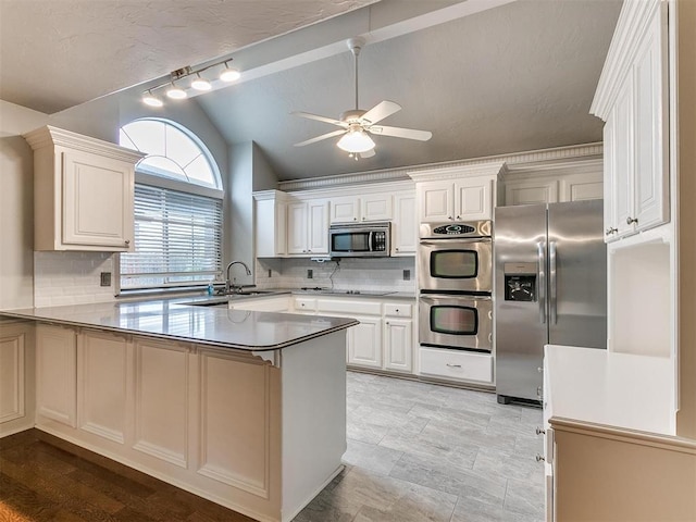 kitchen featuring appliances with stainless steel finishes, kitchen peninsula, vaulted ceiling, and white cabinets