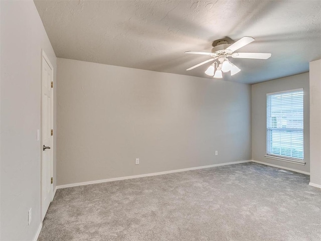 unfurnished room with ceiling fan, light carpet, and a textured ceiling