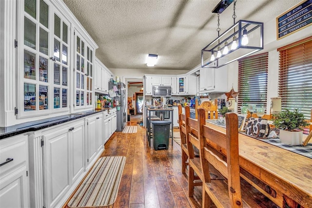 kitchen featuring hanging light fixtures, white cabinets, stainless steel appliances, and a textured ceiling