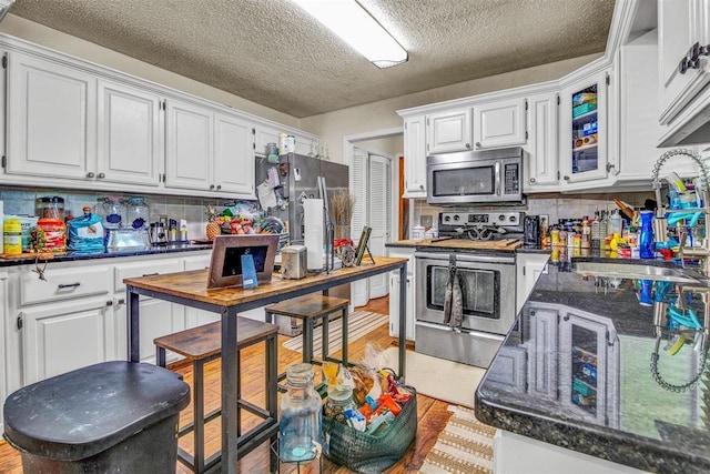 kitchen with white cabinetry, appliances with stainless steel finishes, a textured ceiling, and tasteful backsplash