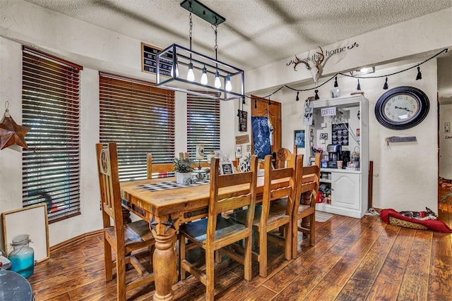 dining space with dark wood-type flooring and a textured ceiling