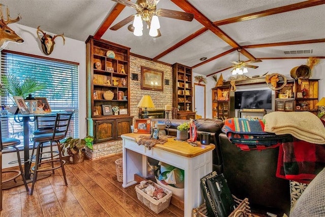 living room with hardwood / wood-style floors, ceiling fan, lofted ceiling with beams, a textured ceiling, and built in shelves