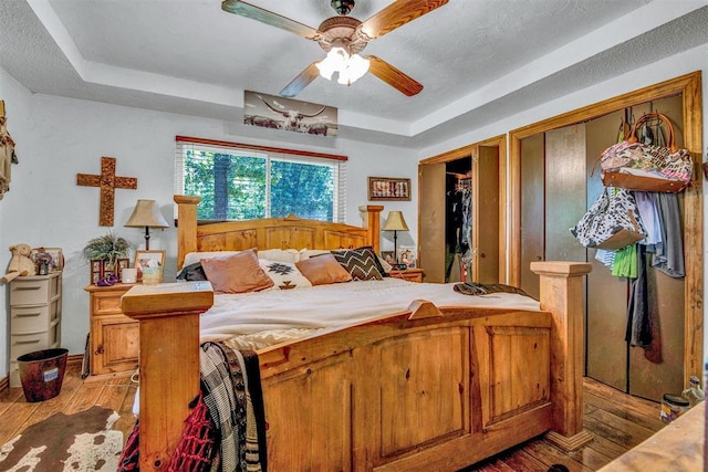 bedroom featuring ceiling fan, a tray ceiling, and hardwood / wood-style flooring