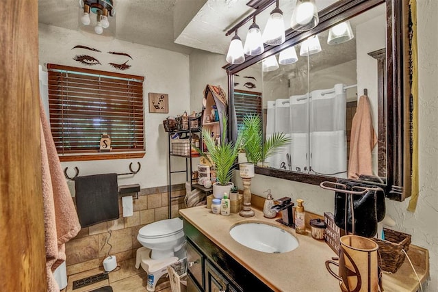 bathroom with toilet, vanity, tile walls, tile patterned flooring, and a shower with shower curtain